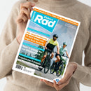 Person in beigem Strickpullover hält das Magazin „ElektroRad“ Ausgabe 05/2023 mit Titelbild zweier Radfahrender in Helmen auf E-Bikes vor bergiger Landschaft; sichtbare Überschriften: „Für neue Horizonte – 13 SUV-Bikes mit High-End-Technik“, „Test: 11 Sättel für top Sitzkomfort“, „Fränkische Schweiz: Ein Paradies für Radler“ sowie orangefarbene Leiste „Sommerglück: Hitze-Tipps für Mensch und Maschine“.