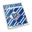 Schräg fotografiertes Magazin mit weißem Cover vor schwarzem Hintergrund. Große blaue Aufschrift „11FREUNDE“, darunter „Magazin für Fußballkultur“; blau-weißes geometrisches Muster, zentrales rot umrandetes 11FREUNDE-Logo und unten der Text „SONDERHEFT 2026/27“.