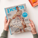 Titelblatt der Zeitschrift „petra“ mit einer weiblichen Person in einem langärmligen, gestreiften Kleid in Pastellfarben und rotem Gürtel vor hellem Hintergrund. Sichtbare Texte: „DIE NEUE SOMMERMODE“, „Stylishe Beach-Bags“, „Lässige Kleider“, „Schöne Bade-Outfits“, „Coole Sonnenbrillen“, „Traumhaft schöne Haare“, „Endlich Zeit zum Lesen“, sowie ein blauer Kreis mit „Die besten Supplements“. Hände halten das Magazin.