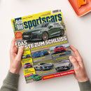 Titelblatt des Magazins „Auto Bild sportscars“, Ausgabe August 2024, gehalten von einer Person mit hellgrünem Strickpullover vor hellem Hintergrund. Großes Titelbild zeigt einen grünen Audi RS 3 competition limited; darunter kleinere Fotos von fünf weiteren Sportwagen verschiedener Marken. Textüberschriften thematisieren Tests, Technik, Neuerscheinungen und Rubriken rund um sportliche Autos.