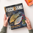 Titelblatt des Magazins „Fisch & Fang“, gehalten von zwei Händen auf hellem Hintergrund. Auf dem Cover liegen zwei Fische – ein goldgrüner Barsch und ein silbrig-roter Weißfisch – auf dunklem Netz. Hauptüberschrift in großen gelben Buchstaben „Aal modern – Mit Köfi-Kopf am T-Rig“, weitere Texte u. a. „Schichtwechsel“, „Räuchern“ und „Fallensteller“. Oben Logos „Parey“ und „Filme“, unten Website „fischundfang.de“.