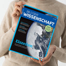 Person in beigem Strickpullover hält ein Magazin mit blau-schwarzem Titelrand „Bild der Wissenschaft“ (Ausgabe 07 | 2026). Auf dem Cover ist eine teilweise vereiste Erdkugel aus dem Weltall zu sehen. Schriftzüge: „Eiszeiten – Kosmische Einflüsse, Klimachaos und Schicksalsmacht für die Menschheit“ sowie kleinere Themen wie „Insekten-Navigation“, „Sportmedizin“ und „Schlafforschung“.