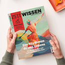 Titelblatt der Zeitschrift „ZEIT Wissen“ mit farbiger Illustration einer dynamisch tanzenden, menschlichen Figur in leuchtenden Tönen aus Rot, Gelb, Grün und Blau vor pastellgrünem Hintergrund. Aufschrift: „Der Rhythmus deines Lebens – Wie du ihn findest und dich von ihm tragen lässt“. Roter Seitenbalken links mit Text „Besser wohnen – Inspirationen aus Japan für ein schöneres Zuhause“. Zwei Hände in grünen Ärmeln halten das Heft.