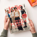Titelblatt der Zeitschrift „jolie“, gehalten von zwei Händen über hellem Untergrund. Im Mittelpunkt stehen fünf weibliche Models in neutralfarbiger Sommermode, bestehend aus Tops und weiten Hosen. Große rosa Überschrift „THE BIG SUMMER ISSUE“, weitere Textelemente: „Festival Guide – Wo wir feiern, was wir tragen“, „Beauty-Hot-List“, „Endlich Zeit zum Lesen“, „Statement Kleider, Beachwear, Sonnenbrillen, Travel-Looks“.