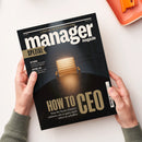 Titelblatt des „manager magazin SPEZIAL“ mit schwarzem Hintergrund und goldener Schrift, zentral ein leerer goldfarbener Chefsessel hinter einem dunklen runden Tisch unter Spotlicht. Sichtbare Textelemente: „HOW TO CEO“, „Was Sie heute können müssen, um es ganz nach oben zu schaffen“, „Netzwerke“, „Achtung, Ego!“ und „Vergütungs-Check: Wo man am besten verdient“. Zwei Hände halten das Heft über hellem Tisch mit oranger Ablagebox.