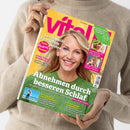 Person in beigem Strickpullover hält eine Ausgabe der Zeitschrift „vital“ mit gelbem Hintergrund und großem lilafarbenem Logo. Auf dem Cover eine lächelnde Frau mit blondem Haar und grünem Oberteil. Textaussagen: „Abnehmen durch besseren Schlaf“, „So schmeckt Spargel am besten“, „ADHS, Trauma, Autismus & Co.“, „Sonnenschutz für jeden Hauttyp“, „Wie die Schulter wieder rund läuft“, „Heilsame Orte zum Durchatmen“.