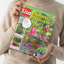 Person mit hellem Pullover hält eine Gartenzeitschrift mit dem Titel „Lisa Blumen & Pflanzen“ (Ausgabe August 2026). Das Cover zeigt einen farbenfrohen Sommergarten mit Dahlien, Zinnien und Gladiolen sowie einen Holztisch mit Metallkorb. Sichtbare Texte: „Bunte Blütenfülle – Endlich Dahlienzeit!“, „Erntestück im Topfgarten: Gemüse zum Snacken“, „Die besten Praxis-Tipps für den Sommer“ und „jetzt freuen wir uns auf …“.
