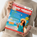 Person in beigem Pullover hält die Reisemagazin-Ausgabe „Clever reisen!“ mit rotem Titelkopf und weißer Schrift „Reise-Insider seit 1986“. Titelbild zeigt eine weiblich gelesene Person in türkisfarbenem Kleid und Strohhut an einem tropischen Strand mit Palmen und blauem Meer. Textausschnitte: „Über 500 Reisetipps“, „Costa Spanien!“, „Insel Poel“, gelber Button „EXTRA FineHotel“.