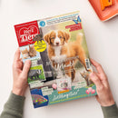 Zwei Hände halten die Zeitschrift „Ein Herz für Tiere“. Auf dem Cover ist ein braun-weißer Hund vor grünlichem Hintergrund abgebildet. Textelemente: „Mit dir ist immer Urlaub!“, „Warum das Flusspferd kein Nilpferd ist“, „Schmetterlinge – Geheimnisse der elfenhaften Wesen“ und „Partymotto Lieblingstier“. Am unteren Rand sind Fotos eines Fisches, eines Dachses, zweier Kaninchen und einer Wildkatze zu sehen.