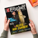 Titelblatt der Angelzeitschrift „Blinker“ mit einem männlichen Angler, der einen großen, goldgelb schimmernden Zander in beiden Händen hält. Der Mann trägt eine dunkle Outdoorjacke und Stirnlampe, Hintergrund ist nächtliche Naturumgebung. Hauptüberschrift in gelber Schrift: „ALLES AUF ZANDER!“. Weitere Texte: „Plattfisch-Massen an deutschen Stränden“, „Juni: Was beißt jetzt am besten?“ und kleinere Themenzeilen am unteren Rand.