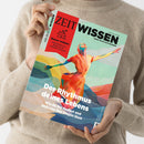 Person mit beiger Strickpullover hält die Zeitschrift „ZEIT WISSEN“ in beiden Händen, Titelmotiv mit abstrakter farbenfroher Illustration einer tanzenden Figur in Rot-, Blau- und Gelbtönen, Text auf dem Cover: „Der Rhythmus deines Lebens – Wie du ihn findest und dich von ihm tragen lässt“, rotes Feld oben links mit Aufschrift „Besser wohnen – Inspiration aus Japan für ein schöneres Zuhause“.