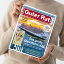 Hellhäutige Person in beigefarbenem Strickpullover hält das Magazin „Guter Rat“ mit rotem Titelkopf und weißer Schrift. Das Cover zeigt ein großes Kreuzfahrtschiff auf dem Meer bei Sonnenuntergang, darüber Texte wie „Das große Kreuzfahrt-ABC“, „Routen – Kosten – Sicherheit“, „Elektrische Zahnbürsten im Test“ und „Gesundes Grillen – Wie Sie ohne Schadstoffe genießen“. Farbtöne in Rot, Blau, Gelb und Weiß, Hochformataufnahme vor neutralem Hintergrund.