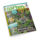 Titelblatt der Gartenzeitschrift „gartenspaß“, Ausgabe Juli 2026. Zentral ein Foto eines blühenden Cottage-Gartens mit Holztisch und zwei Stühlen, umgeben von dichten Blumen in Lila-, Gelb- und Grüntönen. Textelemente: „Gärtnern leicht gemacht“, „20 lässige Gestaltungstipps – Blütenfest im Cottage-Garten“, „Schritt für Schritt“, „Tolle Taglilien“, „Süße Sommerfrüchte“ und „Schatten­glück“.