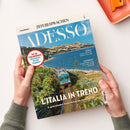Magazin „ADESSO“ aus der Reihe „ZEIT SPRACHEN“, gehalten von zwei Händen über hellem Hintergrund. Das Cover zeigt eine italienische Küstenlandschaft mit einem türkisfarbenen Zug, Schienen, grüner Vegetation und blauem Meer unter klarem Himmel. Sichtbare Texte: „FIT IN ITALIENISCH! Wortschatz für die Zugfahrt“, „L’ITALIA IN TRENO – 8 spektakuläre Zugstrecken für Ihren Urlaub“, „MUSICA“, „L’INTERVISTA“.