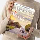 Person in beigem Strickpullover hält schräg eine Zeitschrift mit dem Titel „ZEIT SPRACHEN – ADESSO“ und der Aufschrift „ITALIENISCH“. Das Cover zeigt eine italienische Landschaft mit Straße, weißem Auto und See; lesbare Texte: „Neu! Mehr einfache Texte für mehr Lesespaß“, „Urlaub am LAGO? Ja, aber in Umbrien!“, „Lago Trasimeno“, „VIAGGI“, „ATTUALITÀ“ und „LINGUA“.