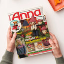 Schräg gehaltenes Titelbild der Handarbeitszeitschrift „Anna“ mit dem Text „Ideen zum Selbermachen • Kreativ und aktuell“ und „Verliebt in Herbstmaschen“. Abgebildet sind gehäkelte Figuren, ein Fuchs auf einem Schlitten, eine blonde Frau im Strickpullover sowie Bastelarbeiten; zwei Hände mit grauen Ärmeln halten das Heft, oben rechts liegt ein orangefarbenes Objekt.