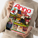 Diagonal gehaltene Zeitschrift „Anna“ mit weißem Cover, rotem Titel und den Aufschriften „IDEEN ZUM SELBERMACHEN • KREATIV UND AKTUELL“, „30 Ideen für deine Wohlfühlzeit!“ und „Verliebt in Herbstmaschen“. Abgebildet sind gehäkelte Figuren, ein gehäkeltes Flugzeug, ein Pullover, Kissen, Teller und ein gestrickter Kürbis; eine Person im beigen Strickpullover hält das Heft mit beiden Händen.