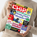 Weiblich gelesene Person in beigefarbenem Strickpullover hält eine schräg fotografierte CHIP-Zeitschrift mit beiden Händen. Das Cover zeigt die Texte „CHIP“, „4 DVDs! Virenfrei & CHIP geprüft“, „Systemstart + Suche + Software“, „Tempo-Tricks für Windows 11“, „Festung FritzBox!“, „Gefahr oder Chance? Mythos-KI“ und „Praxis-Test: OpenClaw“ sowie Abbildungen von DVDs, Software und einem Laptop.