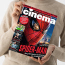 Weibliche Person mit beigefarbenem Strickpullover hält eine schräg ausgerichtete, glänzende Filmzeitschrift in beiden Händen. Das rot-schwarze Cover zeigt eine Spider-Man-Maske sowie die Texte „EXKLUSIVE Die coolsten Film-Locations in NEW YORK“, „IM CHECK!“, „SPIDER-MAN“ und „Das große Special zum Kinostart von ‚Brand New Day‘“.