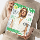 Hochformatiges, schräg gehaltenes GLAMOUR-Magazin aus glattem Papier in den Händen einer Person mit beigefarbenem Strickpullover. Das Cover zeigt eine blonde weibliche Person und enthält die Texte „THE MONEY ISSUE“, „FUN. FEARLESS. FEMALE.“, „Charis-ma? Charis-me!“ sowie weitere grüne und schwarze Schlagzeilen zu Geld, Beziehungen und Alltag.