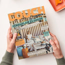 Auf einem weißen Tisch halten zwei Hände ein schräg liegendes Magazin mit orangefarbener Überschrift „COUCH“ und dem Text „ALLES, WAS DU LIEBST“. Das Cover zeigt eine Frau mit weißem Hund im Wohnzimmer sowie die Aufschriften „FERIENFLAIR ZU HAUSE“, „URLAUBS-VIBES“, „EUROSUMMER“, „MEERFARBEN“, „Coolcation“, „Strandgut upcycling“ und „Perfekte Reisebegleiter“.