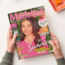 Titelblatt der Zeitschrift „Mädchen“ mit rosafarbenem Logo oben und einer lächelnden weiblichen Person mit langen braunen Haaren, pinkem Oberteil und rosa-weißer Perlenkette im Mittelpunkt. Textelemente: „Wir feiern 50 Jahre“, „We ♥ Summer“, „K-Beauty Mega-Hype aus Korea“, „Dein Ferienflirt“, „Trendy Schmuck-Set“, „Foto-Fun mit der BFF“. Hintergrund grün mit floralem Muster, gehaltene Zeitschrift vor hellem Untergrund.