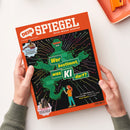 Orangefarbenes Magazin „DEIN SPIEGEL“ mit dem Untertitel „Durch Wissen wachsen“, schräg auf einer weißen Fläche liegend und von zwei Händen gehalten. Das Cover zeigt eine grüne Roboterfigur mit bunten Leiterbahnen sowie die Texte „Wer bestimmt, was KI darf?“, „Von Fake News bis Fake Freunde – warum wir jetzt kluge Regeln brauchen“, „Im Interview Zahnkämpfer Leo Neugebauer“ und „Im Sattel Viktoria Huidl, 13, trainiert Pferde“.