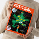 Magazincover „DEIN SPIEGEL – Durch Wissen wachsen“ mit rotem Rand, schwarzem Hintergrund und grüner Roboterfigur in einem bunten Leiterbahn-Muster; eine Person im beigen Strickpullover hält das schräg fotografierte Heft mit beiden Händen. Sichtbare Texte: „Im Interview Zehnkämpfer Leo Neugebauer“, „Wer bestimmt, was KI darf?“, „Im Sattel Viktoria Huld, 13, trainiert Pferde“ und „Von Fake News bis Fake Freunde – warum wir jetzt kluge Regeln brauchen“.