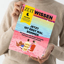 Person in beigem Pullover hält das Magazin „ZEIT Wissen“ (Ausgabe Nr. 04, Juli/August 2023) mit gelbem Kasten „DER MOND – Die große Kraft am Himmel und ihr Einfluss auf die Menschen“ und Titelschrift „JETZT IST ERST MAL SOMMER – Wie man sich von Sorgen frei macht. Und neue Lebenslust gewinnt“. Titelillustration zeigt ein Paar auf Strandstühlen am pinken Sandstrand mit Blick auf Meer und hellblauen Himmel.