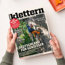 Titelseite des Magazins „klettern – Abenteuer | Lifestyle | Sport“, gehalten von zwei Händen auf hellem Untergrund. Hauptmotiv: eine männliche Person in orangefarbener Hose, blauem Oberteil und Helm klettert an einer steilen Felswand. Textaufschriften: u. a. „Deutschland für Genießer“, „Türkische Riviera“, „Yosemite in Chile“, „Leichte Ausrüstung“ sowie ein roter Kreis mit „Die Not-To-Do Liste“.
