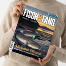 Weibliche Person in beigefarbenem Strickpullover hält ein schräg ausgerichtetes Angelmagazin mit schwarzem Cover. Sichtbare Texte: „FISCH & FANG“, „Das Erlebnis-Magazin für Angler“, „Fishing World + Filme“, „Alle lieben Würmer“ sowie Themen zu Meeresangeln, Angeln am Wasser, Fischküche, Friedfisch und Spinnfischen; abgebildet sind mehrere Fische und Angelausrüstung.