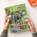 Grünes GEOlino-Magazin im Hochformat, schräg von oben fotografiert und von zwei Händen gehalten; auf dem Cover sind ein Elefant im Wasser, eine männliche Person als „Checker Tobi“ sowie Satelliten abgebildet. Sichtbare Texte: „Die Welt für junge Entdeckerinnen und Entdecker“, „Tierische Klimaschützer“, „Satelliten“, „Werkstatt“ und „GEOlino unterstützt UNICEF“.