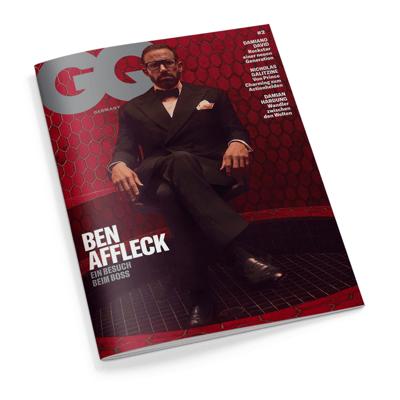 GQ Germany Cover: Ben Affleck sitzt im Anzug und mit Brille vor rotem Hintergrund, mit der Schlagzeile Ben Affleck – Ein Besuch beim Boss.