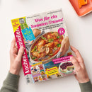 Hochglänzendes Magazin „Kochen & genießen“, schräg von oben fotografiert und von zwei Händen einer Person ohne erkennbares Geschlecht gehalten. Das Cover zeigt „Was für ein Tomaten-Traum!“, ein Ofengericht mit Tomatensoße, weitere Texte wie „Schnell & köstlich: Airfryer-Rezepte“, „Der Pool ruft“ und „Erntefrisch & fruchtig: Sommerkuchen“ sowie ein orangefarbenes Tablett im oberen Bildbereich.