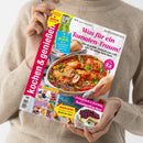 Weibliche Person im beigen Strickpullover hält eine schräg dargestellte Zeitschrift „Kochen & genießen“ mit farbigem Cover. Sichtbare Texte: „Schnell & köstlich: Airfryer-Rezepte“, „Was für ein Tomaten-Traum!“, „Der Pool ruft“, „Italienische Rouladen“ und „Erntefrisch & fruchtig: Sommerkuchen“; abgebildet sind gefüllte Tomaten, Kuchen und weitere Speisen.