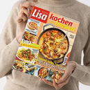 Person in beigefarbenem Strickpullover hält mit beiden Händen ein schräg aufgenommenes Magazin mit dem Titel „Lisa kochen & backen“. Das Cover zeigt Rezeptfotos, darunter einen One-Pot-Süßkartoffel-Topf mit Hackbällchen, sowie die Texte „Einfache Rezepte, die alle begeistern“, „Extra: 16 Seiten Spar-Rezepte“ und „Schnell, lecker, neu: 30-Minuten-Hits“.