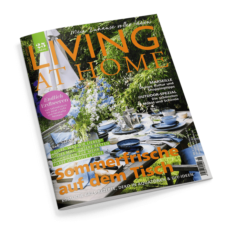 Magazincover LIVING AT HOME: Sommerlich gedeckter Outdoor-Esstisch in einem Garten. Schlagzeilen: Sommerfrische auf dem Tisch, Endlich Erdbeeren.
