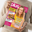 Weibliche Person im beigefarbenen Strickpullover hält ein schräg ausgerichtetes, pink-gelbes Magazin mit dem Titel „plus für mich“. Das Cover zeigt eine blonde Frau sowie die Texte „Gesunde, schöne Haut“, „Das beruhigt den Magen“, „Glanz ins Haar“, „Luxus-Camping in Dänemark“ und „Einmal im Leben …“.