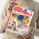 Hochformatige Zeitschrift „selber machen“ mit rotem Titel und gelbem „DIY“-Logo, gehalten von einer Person im hellbeigen Strickpullover. Das Cover zeigt Themen wie „Grill mauern“, „Praxistest“, „Das hält!“, „Platzsparende Balkon-Bar“, „Neue Badideen“ und „So gelingen Ihnen glatte Wände“ sowie Fotos von Renovierungs- und Bauarbeiten.