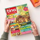 Aufgeschlagenes Magazin „tina Koch & Back-Ideen“ mit grünem Cover, gehalten von zwei Händen mit grauen Strickärmeln. Sichtbare Texte: „Genuss für jeden Tag“, „Mehr als 100 Rezepte“, „Super saftige Hack-Hits“, „Pasta-Glück“, „Mmh, wie fruchtig! Blechkuchen“ und „Süßes mit Schuss“; abgebildet sind Hackbällchen, Kartoffelbrei, Kuchen und weitere Gerichte.