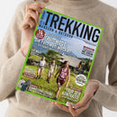 Hochformatige, leicht gedrehte Zeitschrift „TREKKING WANDERN & OUTDOOR“ mit grünem Rand, gehalten von einer Person im beigen Strickpullover. Titeltexte: „Traumwege, die Fernweh wecken – Von Italien bis Irland“, „Irlands Südwesten“, „Trentino“, „Tour der Kontraste“ und „Sommerbekleidung“; das Titelbild zeigt drei wandernde Personen vor alpiner Landschaft.