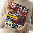Weibliche Person im hellbeigen Strickpullover hält eine schräg ausgerichtete Zeitschrift mit schwarzem und rotem Cover. Sichtbare Texte: „Welt der Wunder“, „ENTDECKEN–STAUNEN–WISSEN“, „Enthüllt: aus den KRANKEN-AKTEN der Mächtigen“, „Die dunkle Psychologie der Weltgeschichte“, „7 TRAUM-STRÄNDE und ihre tödlichen Geheimnisse“ sowie „Das Crime-Experiment: Wie erkennt man ein DEEP-FAKE?“; darunter Collage aus Porträts, historischen Figuren, Palmenstrand und Känguru.